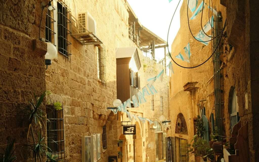 A golden stone alley in Old Jaffa with bunting strung between the walls